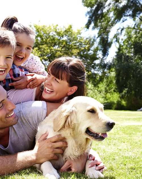 Family Relaxing In Garden With Pet Dog